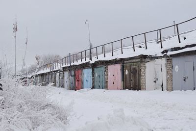 Snow covered field by buildings against sky