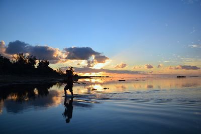 Man standing on beach against sky during sunset