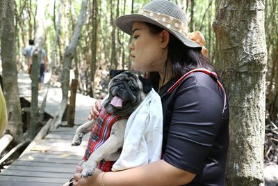 Midsection of woman with dog against trees