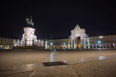 Statue in illuminated city against clear sky at night