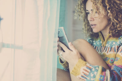 Woman holding mobile phone at home