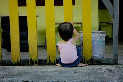 Rear view of girl with yellow umbrella