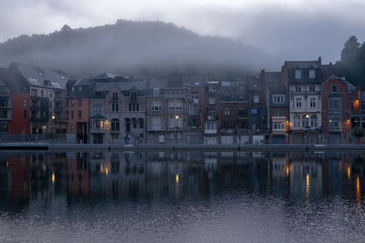 Buildings by lake against sky in city