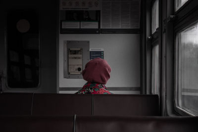 Rear view of woman standing by window at home