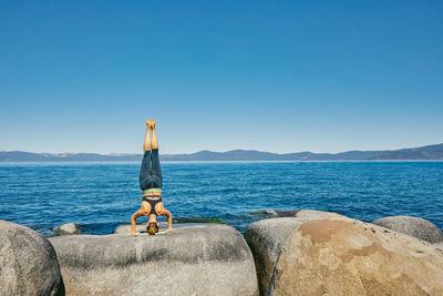 Young woman practicing yoga on lake tahoe in northern california.