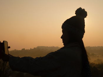 Rear view of man photographing at sunset