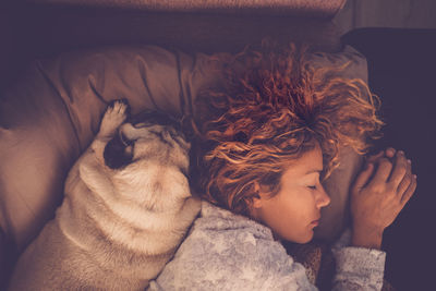 Directly above shot of woman sleeping by dog on bed at home