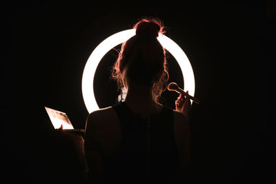 Rear view of woman holding umbrella at night