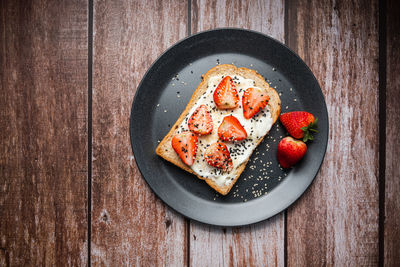 Healthy breakfast toasts with strawberry, yoghurt with whole grain sandwich bread on black dish