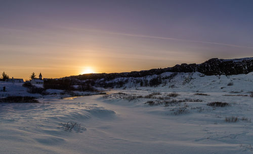 Scenic view of frozen lake against sky during sunset