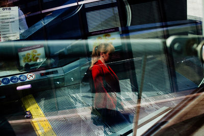 Woman standing by glass window in city