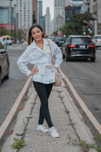 Portrait of young woman standing on street in city