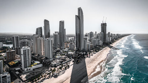 High angle view of modern buildings by sea against clear sky