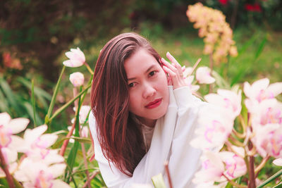 Portrait of woman with pink flowers lying on field