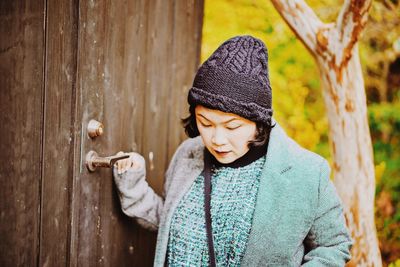 Woman in warm clothing standing against wooden door