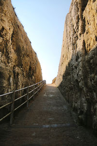 Footpath amidst rocks against clear sky
