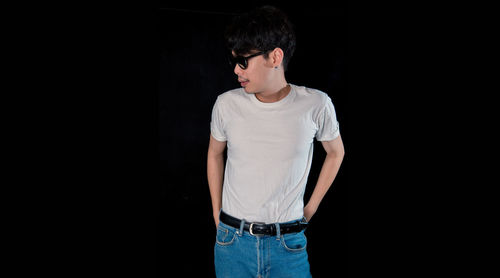 Young man looking away against black background