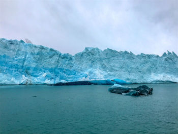 Scenic view of an iceberg with a glacier against sky.