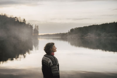 Mature female explorer contemplating by lake during vacation