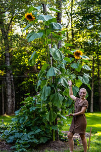 Woman standing by a tall sunflower