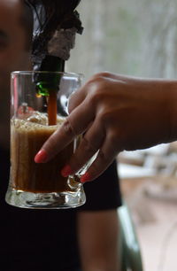 Cropped hand of woman pouring drink in glass