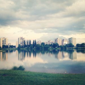 Buildings by river against sky in city