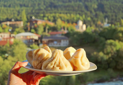 Plate of georgian traditional soup dumplings called khinkali in woman's hand