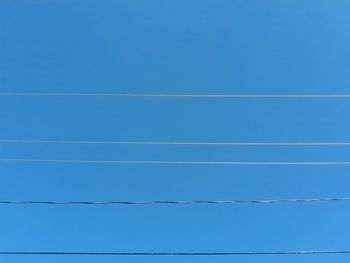 Low angle view of cables against clear blue sky