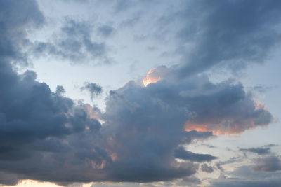 Low angle view of sunlight streaming through clouds