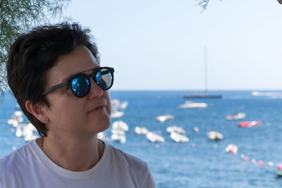 Woman in sunglasses looking away against sea 