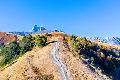 Road leading towards mountain against clear blue sky