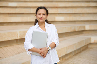 Portrait of young woman standing against wall