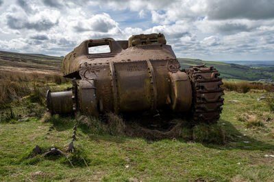 Abandoned vehicle on field against sky