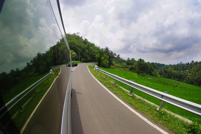 Panoramic view of road amidst trees against sky