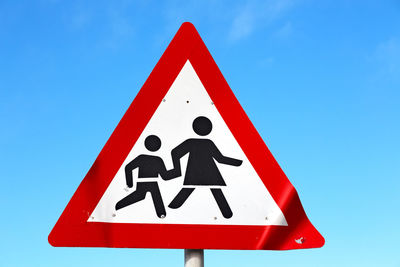 Low angle view of road sign against clear blue sky