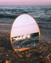 Close-up of sea shore against sunset sky