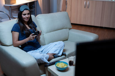 Young woman using mobile phone while sitting on sofa at home