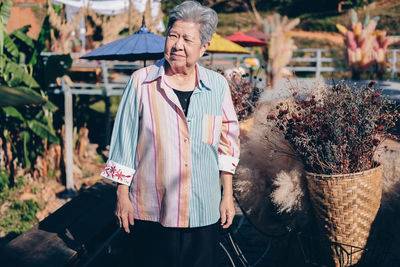 Senior woman looking away while standing outdoors