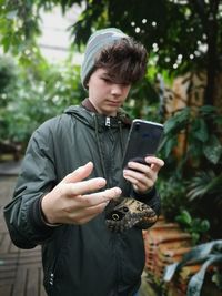 Young man using mobile phone while standing on camera