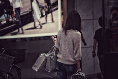 Rear view of woman carrying bags while walking on street