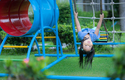 Smiling girl sitting on swing at playground