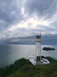 Lighthouse by sea against sky