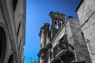 Low angle view of buildings in town against clear blue sky