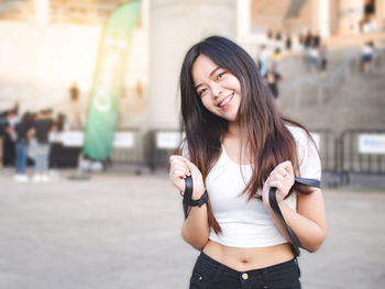 Asian young woman dressed in hipster style, smiling brightly at the camera.