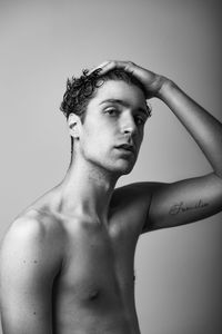 Portrait of shirtless young man against gray background