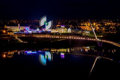 Illuminated cityscape against sky at night
