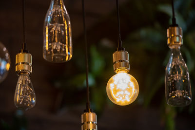 Low angle view of illuminated light bulbs hanging from ceiling