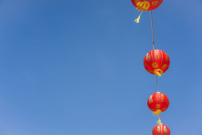 Low angle view of lanterns hanging against clear blue sky
