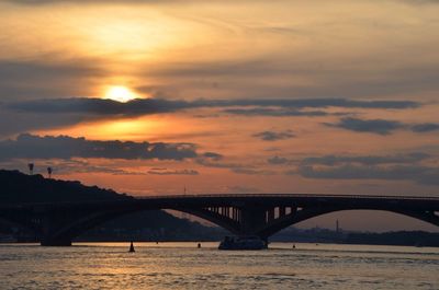 Bridge over river against cloudy sky