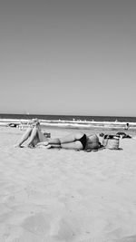 People relaxing on beach against clear sky